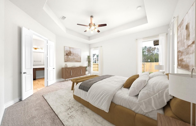 carpeted bedroom featuring a tray ceiling and ceiling fan