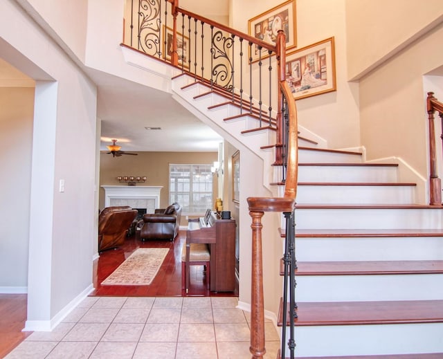 staircase featuring tile patterned floors, ceiling fan, and a fireplace