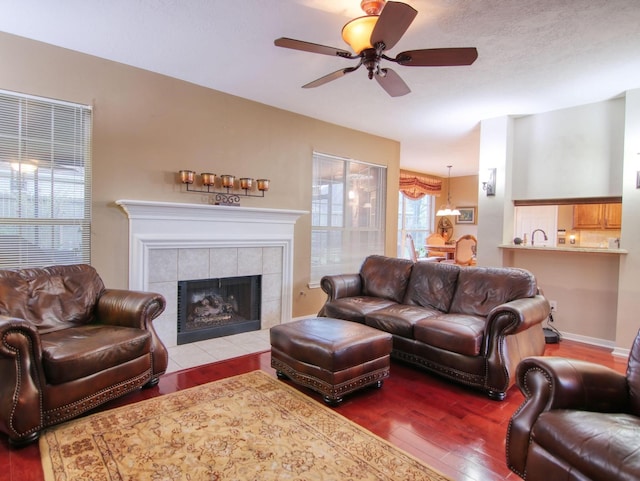 living room featuring hardwood / wood-style floors, ceiling fan, and a tile fireplace