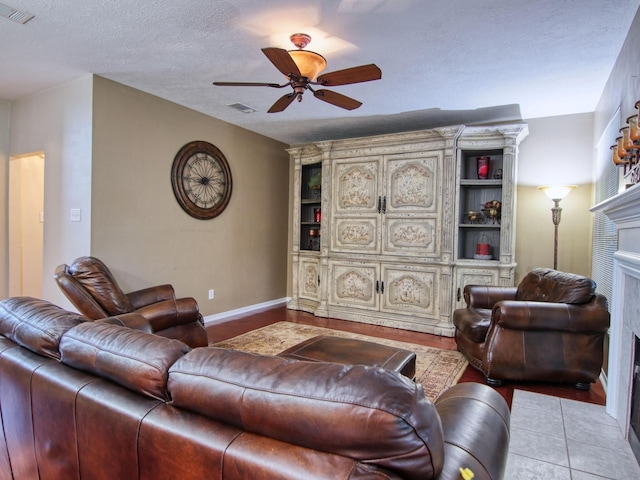 tiled living room featuring ceiling fan and a textured ceiling