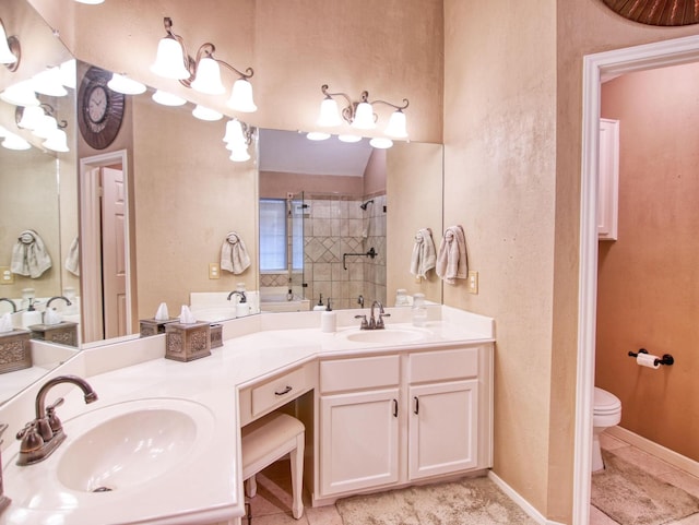 bathroom with tile patterned flooring, toilet, vanity, and tiled shower