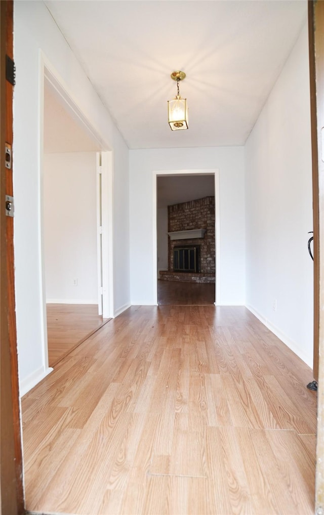 unfurnished living room featuring light hardwood / wood-style floors and a brick fireplace