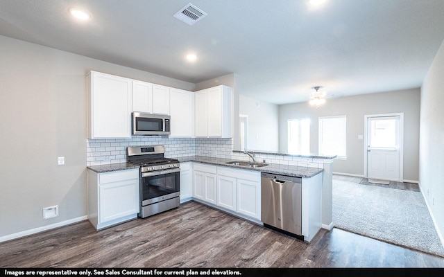 kitchen with white cabinetry, sink, kitchen peninsula, hardwood / wood-style floors, and appliances with stainless steel finishes