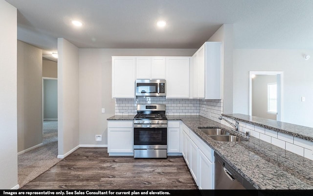 kitchen with light stone counters, stainless steel appliances, sink, white cabinets, and dark hardwood / wood-style floors