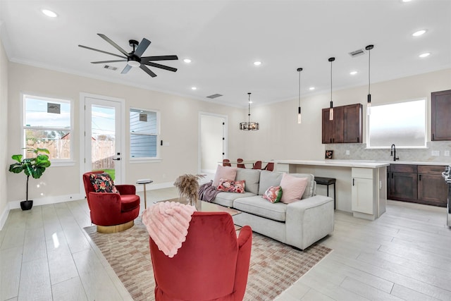 living room with light hardwood / wood-style flooring, ceiling fan, crown molding, and sink