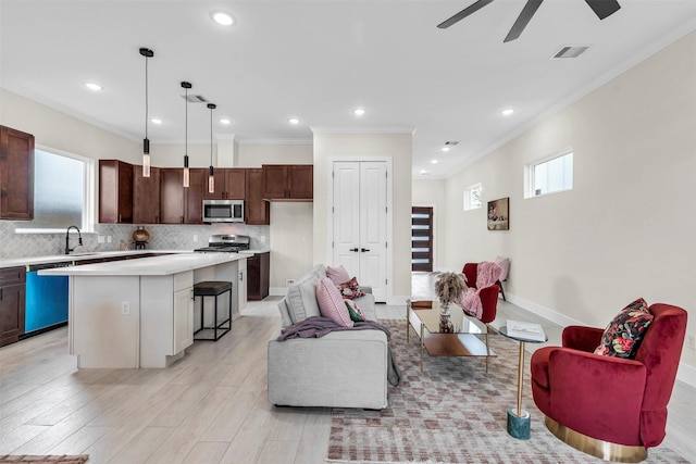 living room with crown molding, sink, ceiling fan, and light wood-type flooring