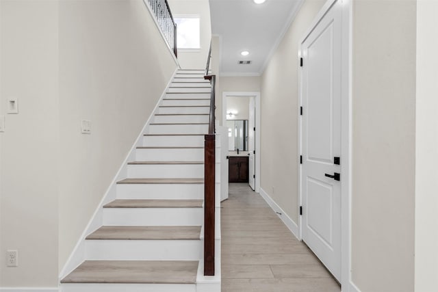 stairs featuring crown molding and wood-type flooring