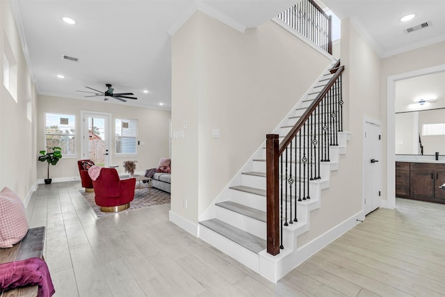 staircase featuring hardwood / wood-style flooring, ceiling fan, and ornamental molding