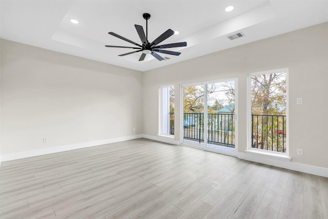 spare room featuring ceiling fan, a raised ceiling, and light wood-type flooring