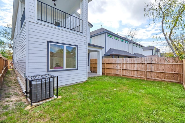 rear view of property featuring cooling unit, a balcony, and a yard