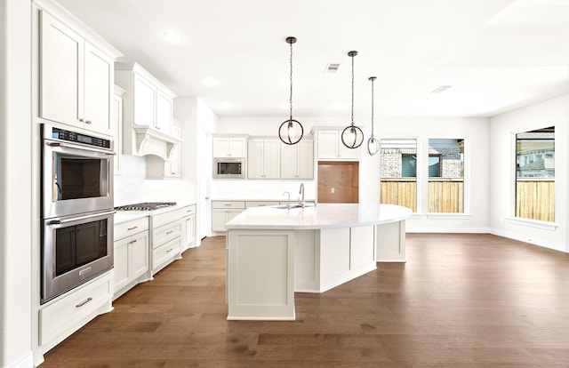 kitchen featuring a center island with sink, a healthy amount of sunlight, white cabinetry, and appliances with stainless steel finishes