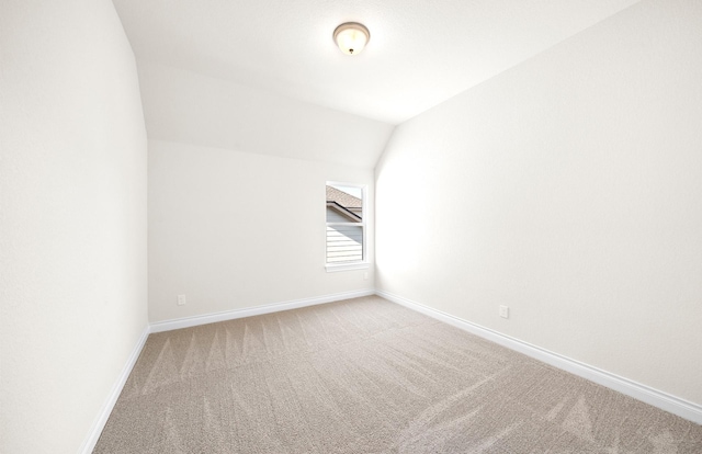 spare room with carpet floors and vaulted ceiling