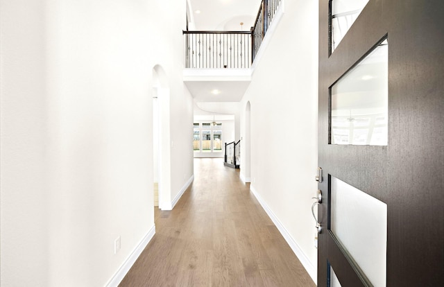 hallway with wood-type flooring and a towering ceiling