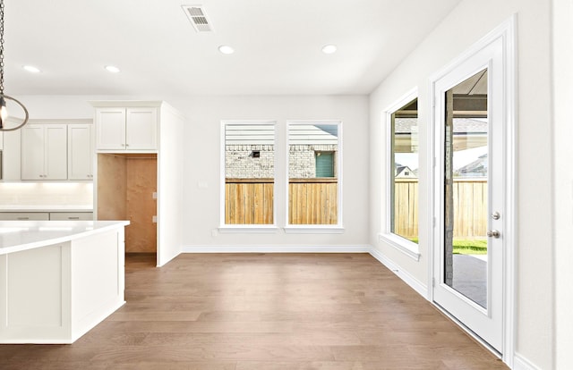 kitchen with light hardwood / wood-style flooring, white cabinets, and hanging light fixtures