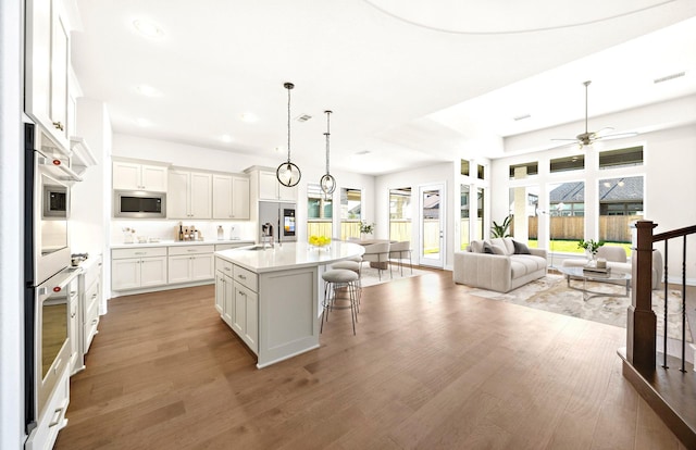 kitchen featuring hardwood / wood-style floors, white cabinetry, an island with sink, and stainless steel appliances