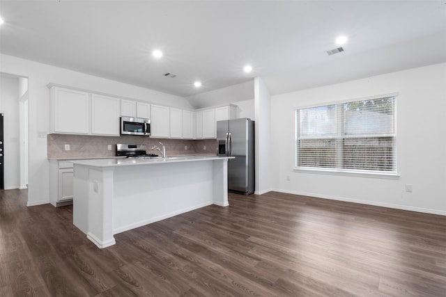 12305 Delta Timber Rd, Conroe, TX 77304 - kitchen with stainless steel appliances, tasteful backsplash, light countertops, a center island with sink, and white cabinetry