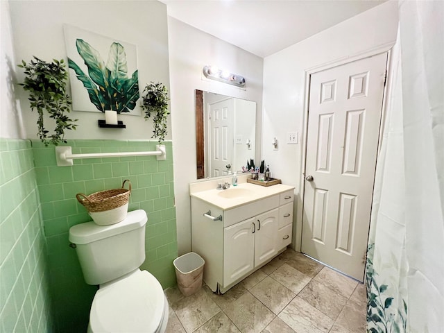 bathroom with vanity, toilet, and tile walls