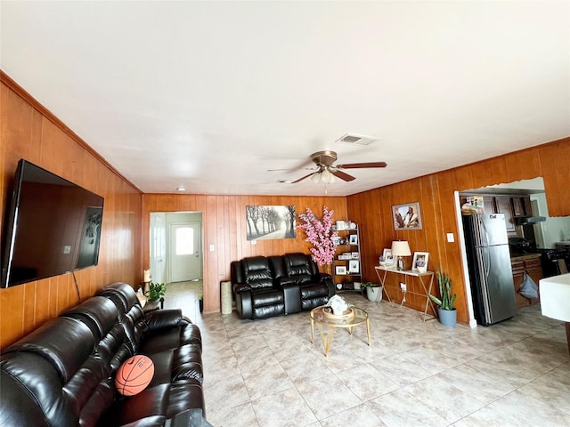 living room featuring ceiling fan, wood walls, and ornamental molding