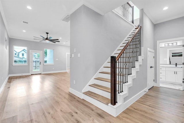 stairs featuring hardwood / wood-style flooring, ceiling fan, and ornamental molding