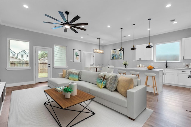 living room featuring ceiling fan, crown molding, and light hardwood / wood-style floors