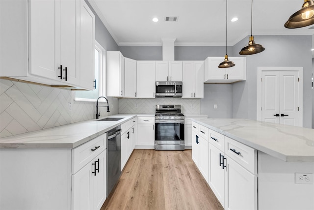 kitchen with light stone countertops, appliances with stainless steel finishes, sink, pendant lighting, and white cabinets