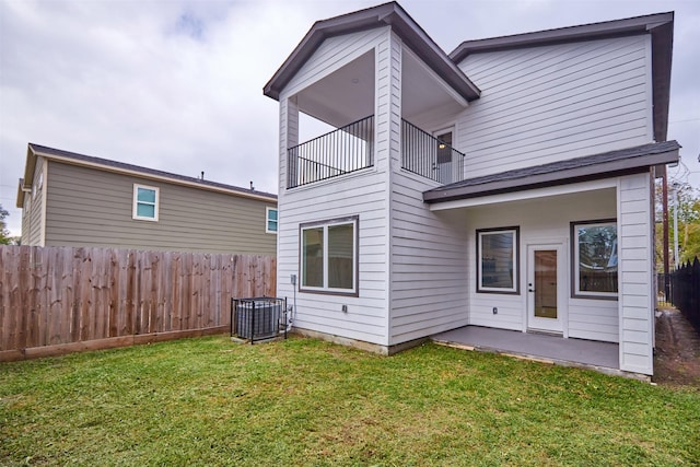 back of property featuring a patio, a balcony, and a lawn