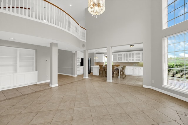 unfurnished living room featuring a towering ceiling, built in features, and a wealth of natural light