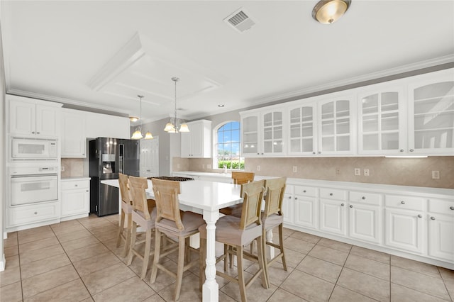 kitchen with white appliances, a center island, and white cabinetry