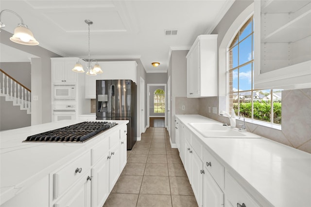 kitchen featuring white appliances, sink, light tile patterned floors, decorative light fixtures, and white cabinets