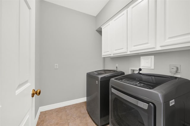 clothes washing area featuring cabinets, washing machine and dryer, and light tile patterned flooring