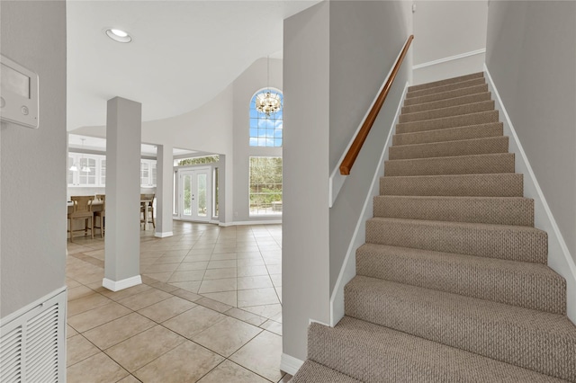 stairway with tile patterned floors, a towering ceiling, and an inviting chandelier