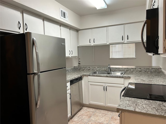 kitchen with light stone countertops, white cabinetry, sink, stainless steel appliances, and light tile patterned floors