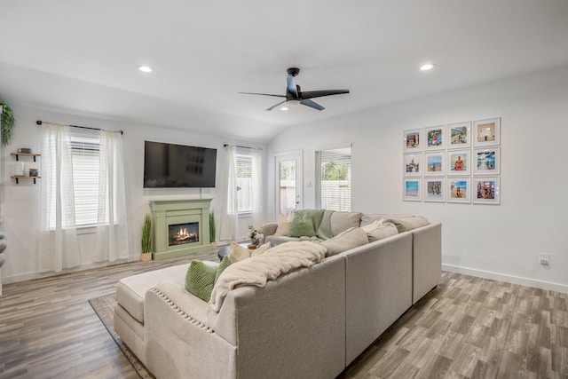 living room with ceiling fan, light wood-type flooring, and vaulted ceiling