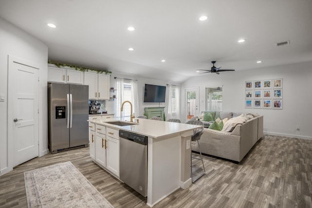 kitchen featuring a center island with sink, sink, white cabinetry, and stainless steel appliances