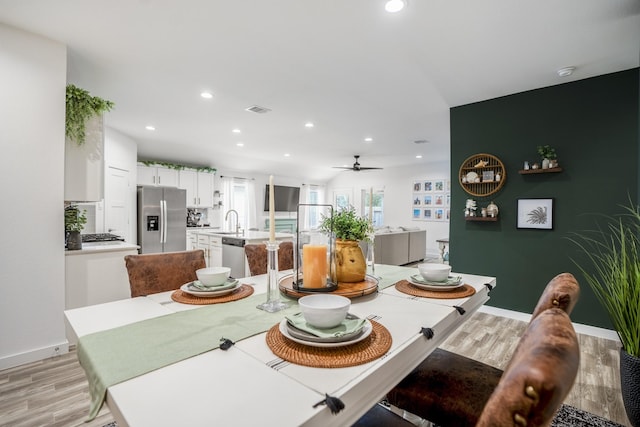 dining area with ceiling fan, light hardwood / wood-style floors, and sink