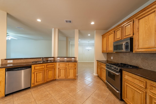 kitchen featuring backsplash, ceiling fan with notable chandelier, sink, light tile patterned floors, and appliances with stainless steel finishes