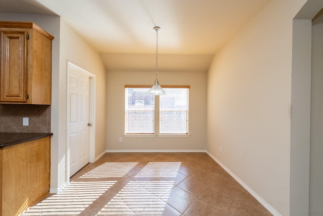 unfurnished dining area featuring light tile patterned floors and vaulted ceiling