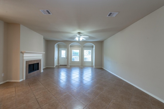 unfurnished living room with a fireplace, light tile patterned floors, and ceiling fan