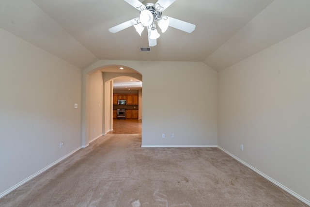 unfurnished room featuring ceiling fan, light colored carpet, and vaulted ceiling