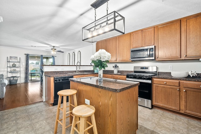 kitchen featuring appliances with stainless steel finishes, a breakfast bar, sink, decorative light fixtures, and a center island