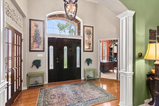 entryway with wood-type flooring, ornate columns, and a towering ceiling