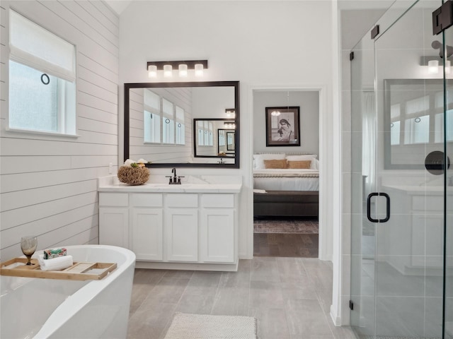 bathroom featuring vanity, wood walls, and separate shower and tub