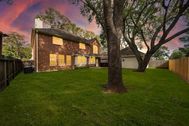 back house at dusk featuring a yard and central AC unit