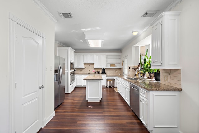 kitchen with a center island, white cabinets, dark hardwood / wood-style floors, dark stone countertops, and stainless steel appliances