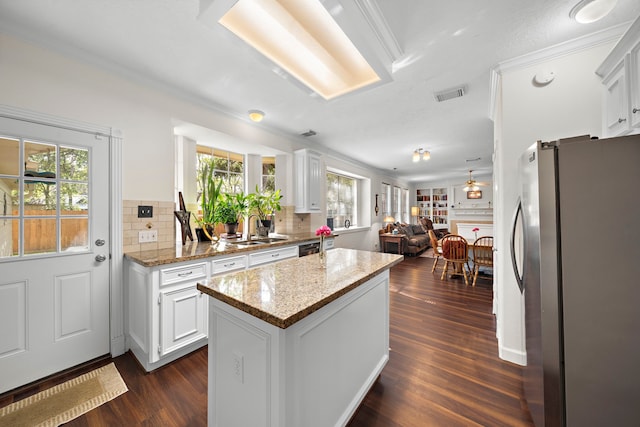 kitchen with white cabinets, stainless steel fridge, backsplash, and a healthy amount of sunlight