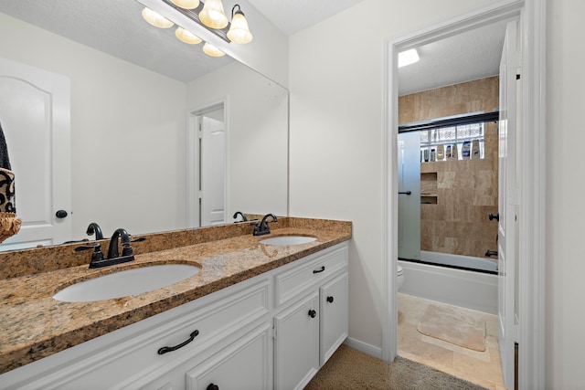 full bathroom featuring vanity, tile patterned floors, combined bath / shower with glass door, toilet, and a textured ceiling