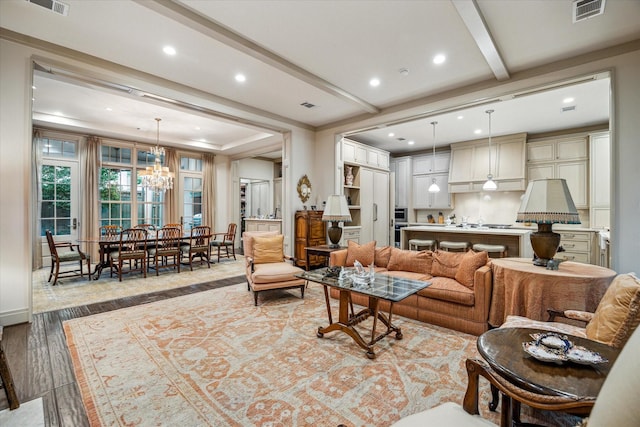 living room with light hardwood / wood-style floors, beam ceiling, and a chandelier