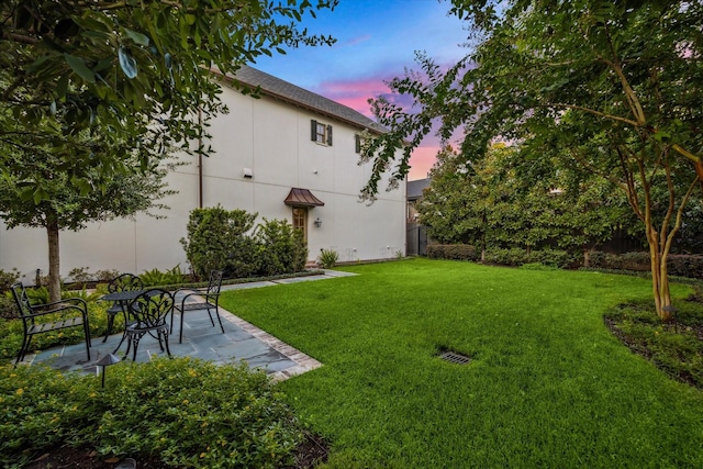 yard at dusk featuring a patio