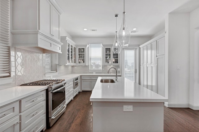 kitchen with stainless steel appliances, a kitchen island with sink, sink, dark hardwood / wood-style floors, and white cabinetry