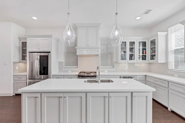 kitchen featuring hanging light fixtures, sink, stainless steel refrigerator, and an island with sink